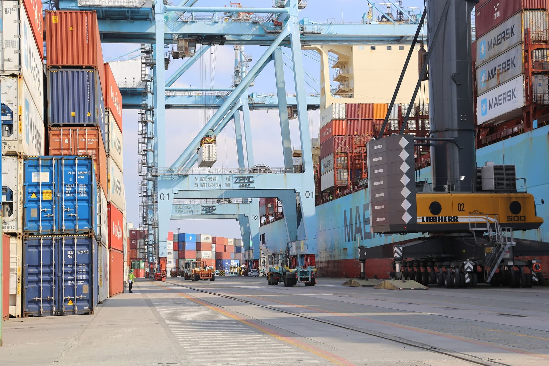 Terminal de contêineres do porto de Itajaí, em Santa Catarina, com guindastes e navio atracado.